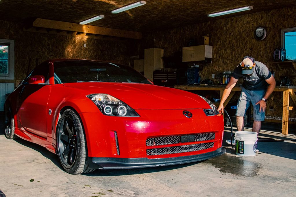 a man washing a red sports car in a garage
